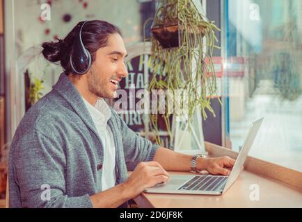 L'homme en souriant ayant un profil côté conversation en ligne, un chat vidéo à la recherche à l'écran de l'ordinateur portable, gesticulant expliquer quelque chose à vivre Banque D'Images