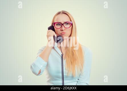 Malentendu et appel distant. Une jeune femme agacée parlant au téléphone frustrée par l'appel isolé sur fond vert clair jaune. Une fille entend une fru Banque D'Images