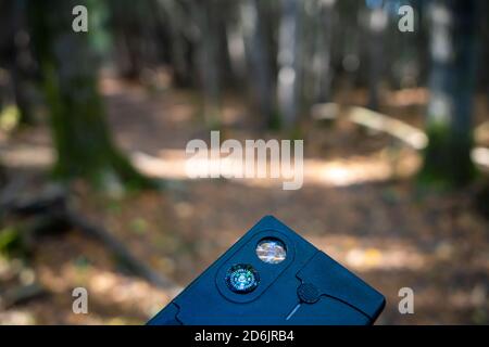 Une petite boussole intégrée dans un multi-outil en forme de carte de crédit est maintenue dans les bois. Banque D'Images