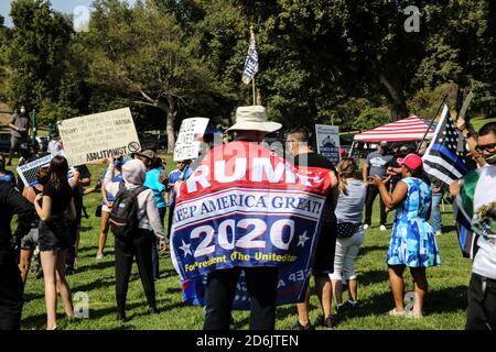 Los Angeles, États-Unis. 17 octobre 2020. Un homme enveloppé dans le drapeau de Trump 2020 se dresse entre les manifestants du BLM et les partisans du LAPD pendant la manifestation.des supporters du département de police de Los Angeles (LAPD) se sont rassemblés à Elysian Park à Los Angeles, en Californie, pour montrer leur soutien au département de police de Los Angeles. Bien que l'événement ait été pour la plupart calme avec un barbecue et de la musique live, les manifestants de BLM sont arrivés à la fin de l'événement et ont protesté le département de police de Los Angeles. Crédit : SOPA Images Limited/Alamy Live News Banque D'Images