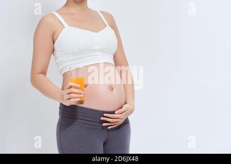 Charmante femme enceinte tenant un verre de jus d'orange tandis que l'article Banque D'Images