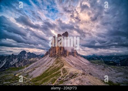 Vue panoramique sur le groupe de montagnes Tre Cime di Lavaredo, vue de Paternkofel Scharte, partiellement couvert de nuages au coucher du soleil. Banque D'Images