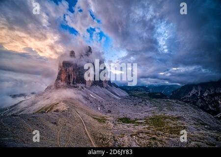 Vue panoramique sur le groupe de montagnes Tre Cime di Lavaredo, vue de Paternkofel Scharte, partiellement couvert de nuages au coucher du soleil. Banque D'Images