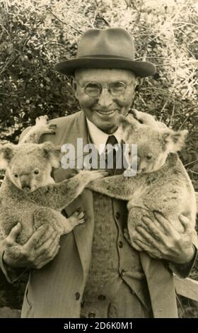 Un homme inconnu qui pose avec deux koalas dans le Queensland, probablement dans les années 1930 au Lone Pine Koala Sanctuary à Brisbane. De la collection de la famille McKechnie. Banque D'Images