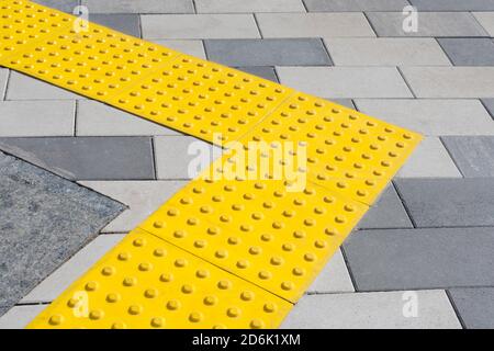 Blocs jaunes de pavage tactile pour handicap aveugle. Blocs en braille, carreaux tactiles pour les malvoyants, blocs Tenji. Surface texturée Banque D'Images