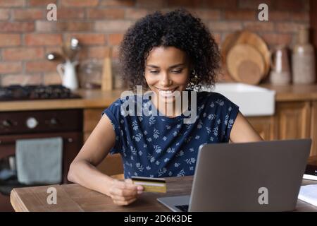 Femme afro-américaine souriante payant en ligne sur ordinateur Banque D'Images