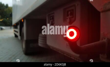 Gros plan du feu de gabarit arrière rond rouge d'un chariot. Feu arrière pour un chariot. L'arrière-plan est flou. Le concept de la sécurité sur la route Banque D'Images