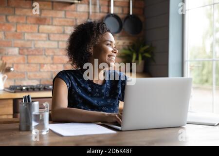 Une femme afro-américaine souriante regarde dans le rêve à distance Banque D'Images