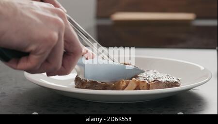 Homme en tranches de steak de ribeye sur une assiette blanche sur un comptoir en béton, photo large Banque D'Images