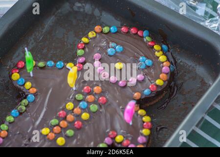 Un gâteau d'anniversaire au chocolat, en forme de personne souriante, décoré de bonbons colorés Banque D'Images