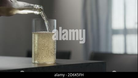 homme verse la boisson gazeuse d'une bouteille dans le verre à bille haute sur le plan de travail en béton avec espace de copie, photo large Banque D'Images