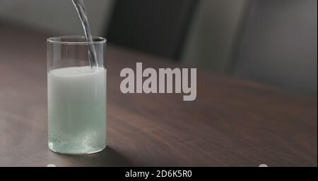 versez la boisson gazeuse verte d'une bouteille dans le verre à bille haute sur la table en noyer avec espace de copie, photo large Banque D'Images