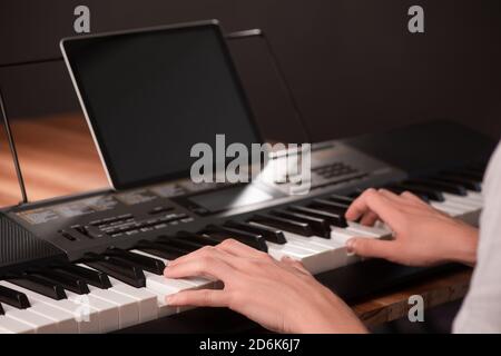 Jeune homme apprenant à jouer du piano, en utilisant le clavier et la tablette avec Banque D'Images