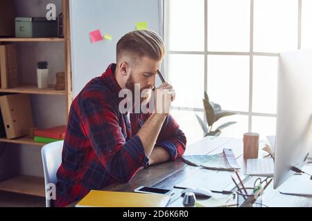 Jeune homme travaillant sur une tablette numérique professionnelle et un ordinateur portable avec un échantillon de couleur sur le bureau en studio. Concept de conception créative Banque D'Images