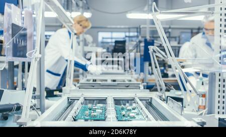 Photo d'un ouvrier de l'électronique assemblant les cartes de circuit à la main alors qu'il est sur la ligne de montage. Usine de haute technologie. Banque D'Images