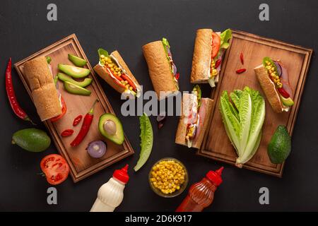 Ensemble d'ingrédients pour les sandwichs au jambon sur une table sombre, vue de dessus. Gros plan Banque D'Images