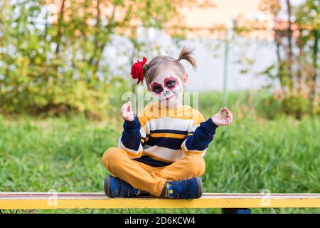 Une petite fille au visage peint, regardant l'appareil photo le jour des morts. Banque D'Images