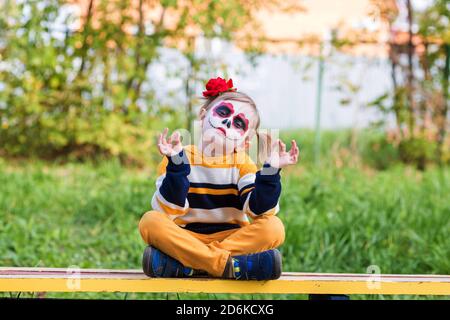 Une petite fille au visage peint, regardant l'appareil photo le jour des morts. Banque D'Images