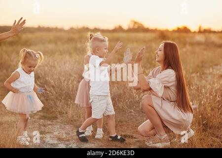 joyeux jeunes mamans jouant avec leurs enfants en plein air en été. Un concept de « famille heureuse ». Foyer sélectif. Banque D'Images