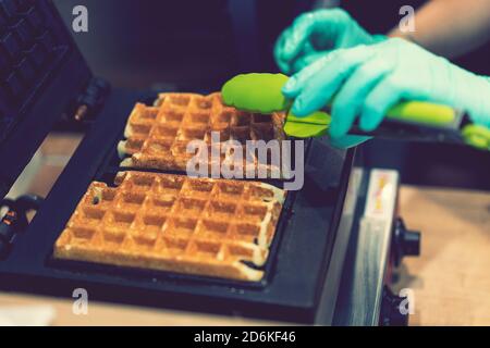 Fer à repasser dans la cuisine. Préparer des gaufres faites maison, verser une pâte. Préparation de gaufres faites maison dans la machine à gaufres double. Mise au point sélective Banque D'Images