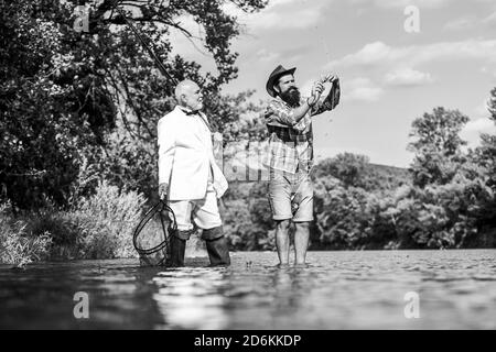 Belle journée pour la pêche. a pris sa retraite père et fils mature avec barbe. Fly fishing adventures. passe-temps des affaires. la retraite. pêche pêcheurs heureux dans l'eau. les amis des hommes avec la canne à pêche et net. Banque D'Images