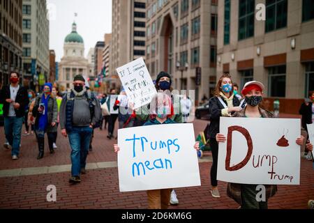 Un jeune enfant portant un masque porte un écriteau à travers la lecture de mars, ?rumps moyen?pendant le rallye des ?rossroads de la démocratie: Jour de l'action. Plus de 100 manifestants se sont rassemblés pour le rassemblement ?rossroads of Democracy: Day of action' à l'extérieur de l'Indiana Statehouse. Le rassemblement a été organisé par les femmes méchants de l'Indiana, et le caucus législatif noir de l'Indiana, et a coïncidé avec les femmes? Des événements d'une journée aux États-Unis pour renforcer les capacités des jeunes Hoosiers et améliorer la participation électorale. Banque D'Images