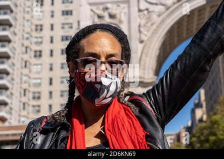 Un manifestant portant un masque facial fait un geste au Washington Square Park pendant la manifestation.des milliers de personnes sont descendues dans les rues à travers les États-Unis pour des marches féminines, dont beaucoup portent des chapeaux de protestation roses tout en émettant des appels fervents contre le président Donald Trump et son choix conservateur de la Cour suprême. Les rassemblements qui ont eu lieu avant l'élection de novembre 3 ont été inspirés par la première Marche des femmes à Washington DC, un énorme rassemblement anti-Trump qui s'est tenu un jour après son investiture de 2017. Banque D'Images