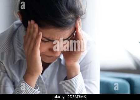 Les temples de contact de fille indienne stressés réduisent l'image de gros plan de mal de tête insupportable Banque D'Images