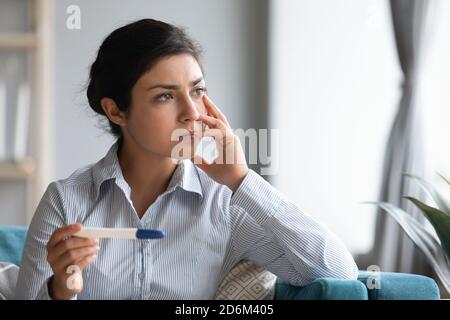 Triste femme indienne tenue test de grossesse regardant par la fenêtre Banque D'Images