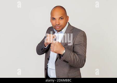 Un jeune homme d'affaires afro-américain semble confiant, en colère, fort et agressif, avec des poings tenant la main devant lui dans une posture de boxe, sur le point de se battre, prêts à se battre. Banque D'Images