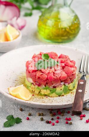 Tartare de thon tartare avec avocat et oignon violet. Servi avec de la coriandre (coriandre), du citron et du poivre fraîchement moulu. Délicieux hors-d'œuvre (salade) de r Banque D'Images