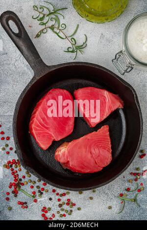 Steaks de thon crus au sel de mer, poivre rose, vert et noir et romarin pour griller ou cuisiner dans une casserole en fonte. Préparez un délicieux dîner. Sél Banque D'Images