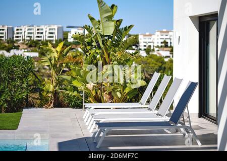 Chaises longues blanches dans la rangée près de la piscine. Vacances d'été et concept de voyage Banque D'Images