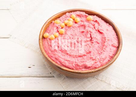 Houmous à la betterave dans un bol en bois sur fond blanc en bois et toile de lin. Vue latérale, gros plan. Banque D'Images