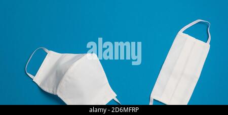 Deux masques médicaux blancs réutilisables sur fond bleu foncé isolé Hygienic chirurgical, antiviral masque concept de l'équipement de protection contre le coronavirus Banque D'Images