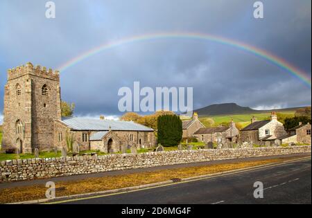 Arc-en-ciel au-dessus de l'église du village de St Oswald dans le Yorkshire village de Horton à Ribblesdale avec la montagne de Pen-y-gand sur la Pennine Way Banque D'Images