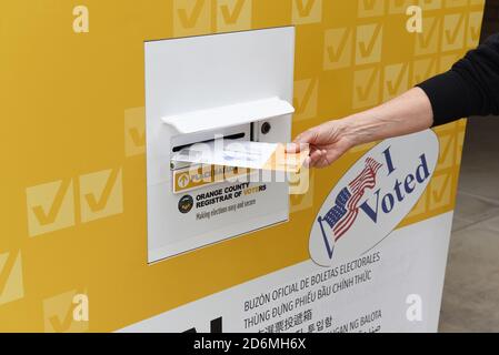 IRVINE, CALIFORNIE - 18 octobre 2020 : une femme qui dépose son courrier dans un bulletin de vote officiel dans un parc public, Irvine, Orange County, Californie. Banque D'Images