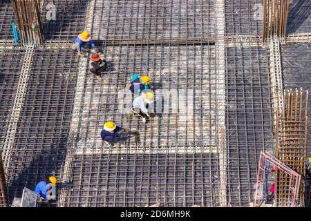 Les ouvriers de la construction fabriquent de grandes barres de renfort en acier sur le chantier de construction de la zone de construction. Banque D'Images