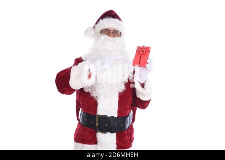 Homme âgé portant un costume traditionnel du Père Noël tenant un petit cadeau en papier rouge d'une main et pointant vers lui de l'autre. Isolé o Banque D'Images