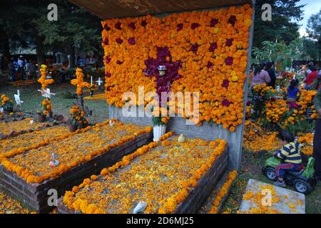 Les familles décorent les tombes de Patzcuaro, au Mexique, au cours de la journée des morts, avec des marigolds traditionnels, ainsi que des aliments et d'autres favoris de leurs proches. Banque D'Images