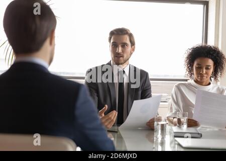 Chef d'équipe confiant à l'écoute des jeunes collègues masculins. Banque D'Images