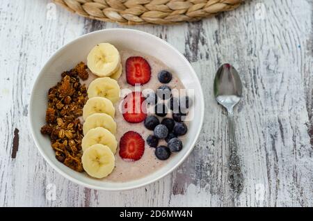 Petit déjeuner sain porridge de flocons d'avoine avec fraises, banane, bleuets et granola Banque D'Images