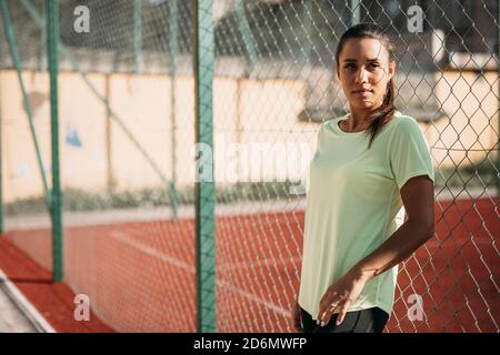 Femme ayant une pause pendant l'entraînement près de la clôture de maillon de chaîne Banque D'Images