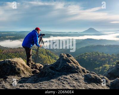 Photographe travaillant en montagne. Photographe de la nature voyageur prenant la photo de beau paysage du matin du haut de la montagne Banque D'Images