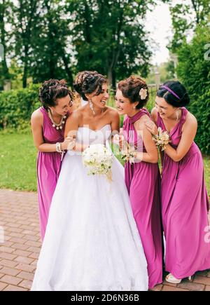 Les demoiselles d'honneur en robes roses épousent la mariée et rient à un mariage italien. Banque D'Images