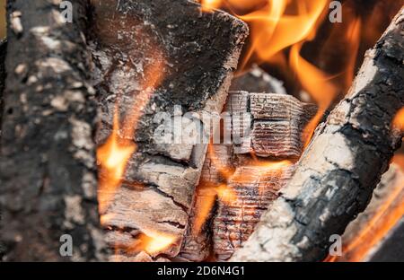 Le bois brûle dans les charbons au niveau du piquet. Arrière-plan des journaux de gravure et des branches. Gros plan. Banque D'Images