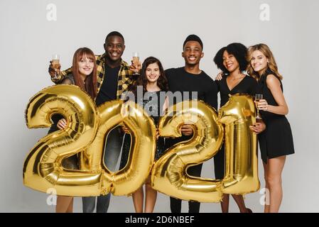 Nouvelle année 2021 est à venir Groupe de jeunes joyeux dans les chapeaux de Santa portant des numéros de couleur or et de boire du champagne. Banque D'Images