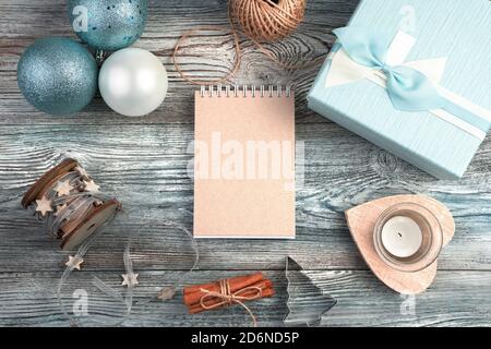 Bloc-notes sur fond de Noël avec boîte cadeau, bougies et boules de Noël sur fond de bois. Banque D'Images