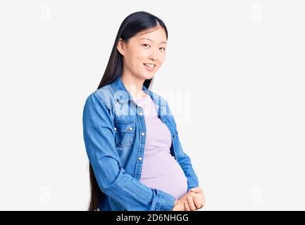 Jeune belle chinoise femme enceinte s'attendant à bébé avec les mains ensemble et les doigts croisés souriant détendu et gai. Succès et optimiste Banque D'Images