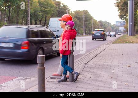 Une petite fille traverse la route à un passage pour piétons. Avertissement enfants sur la route. Panneau d'avertissement pour piétons près de l'école pour enfants. Banque D'Images